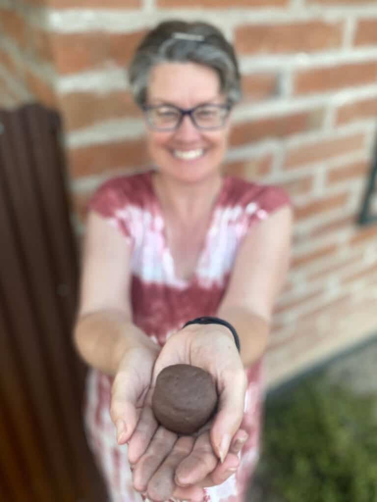 Smiling Ms Davis holding a seed ball in her cupped hands.